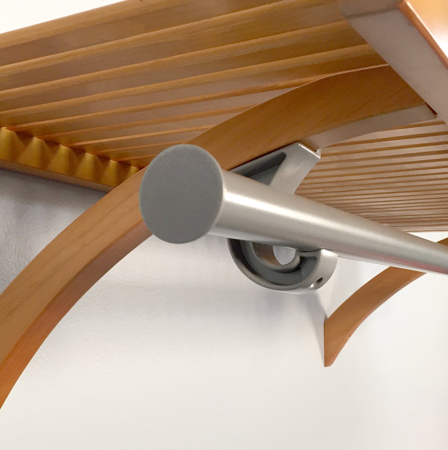 Close-up of a metal wardrobe bar on a honey maple solid wood shelf on a white background