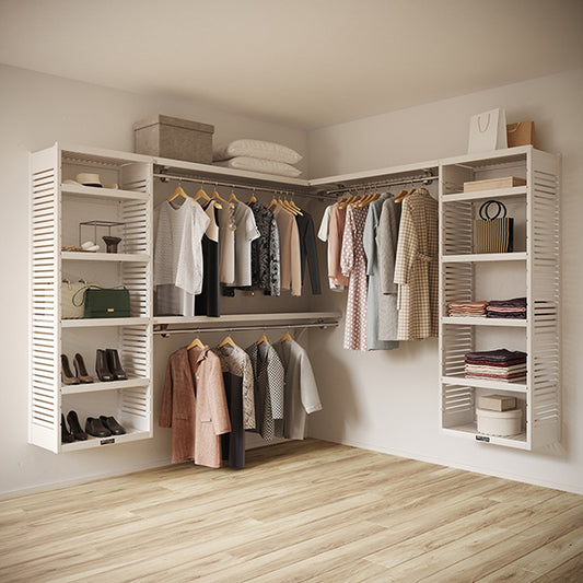 White L Shaped walk in closet organizer with clothes and shoes in a room.