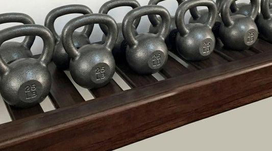 Row of kettlebells on a wooden rack with a neutral background