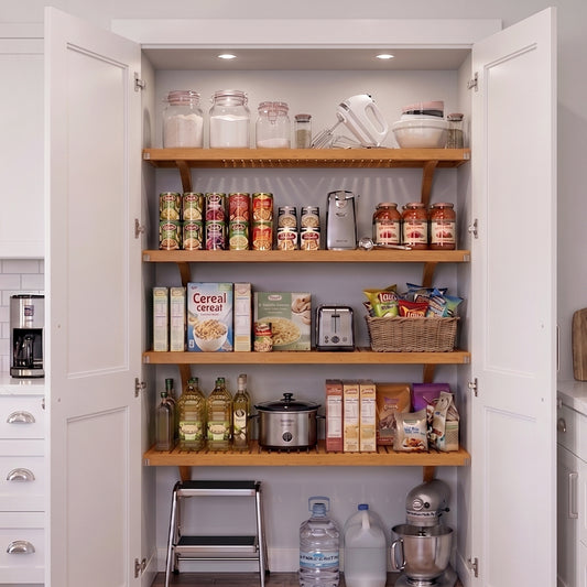 A tall pantry cabinet with open white doors, showing solid wood honey maple shelving stocked with grocery items and kitchen appliances.
