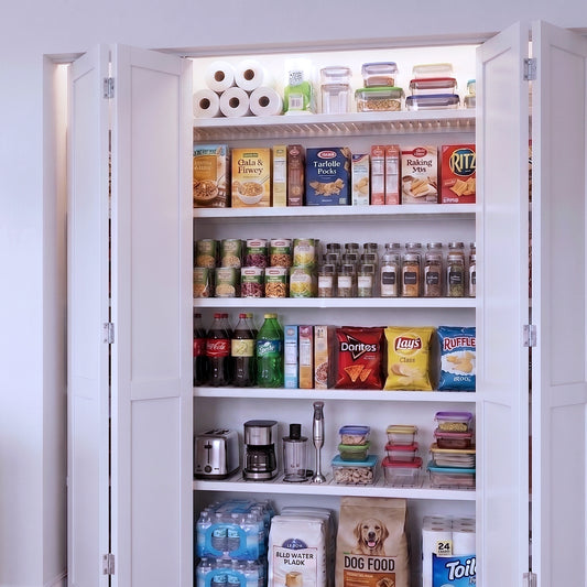 A reach-in kitchen pantry cabinet filled with 5 solid wood white shelves of groceries.