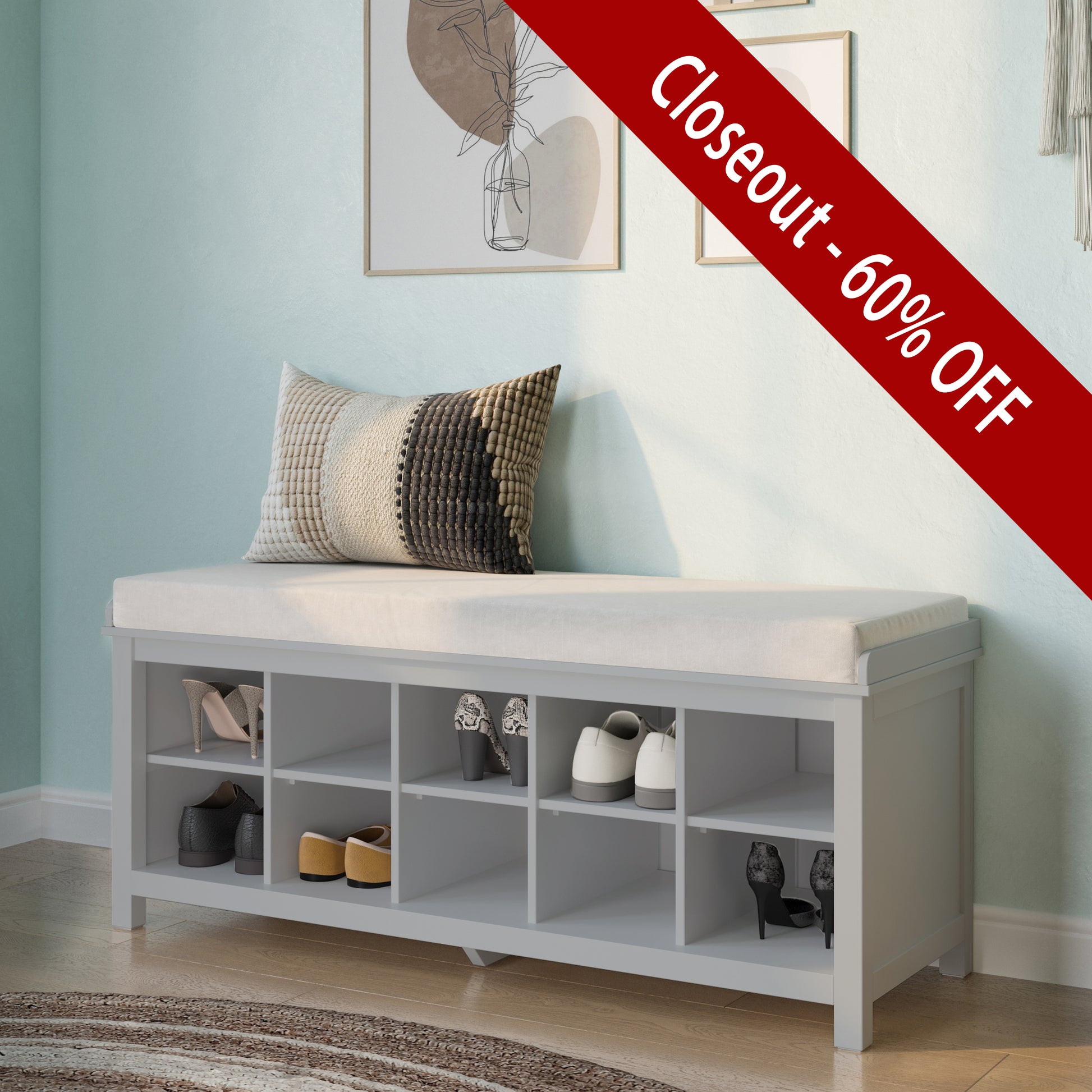 Gray storage bench with cushioned top and shoe storage compartments in a room with light blue walls and framed pictures.