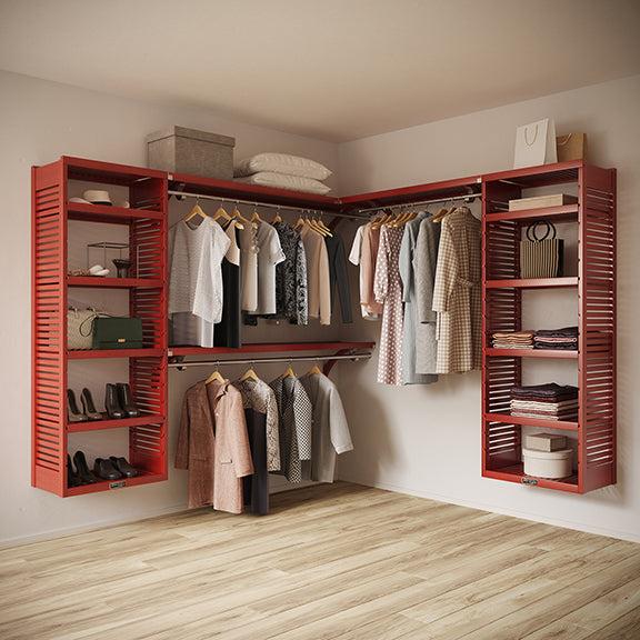 Red Mahogany L Shaped walk in closet organizer with clothes and shoes in a room.