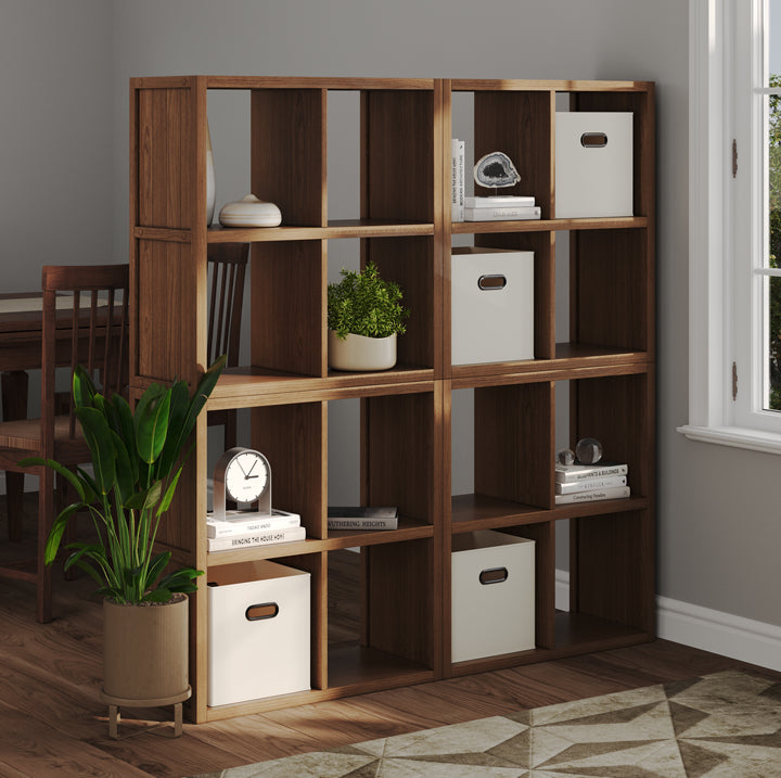 4 Cube wall bookshelf with storage boxes and decor items as a room divider with a window and plant.
