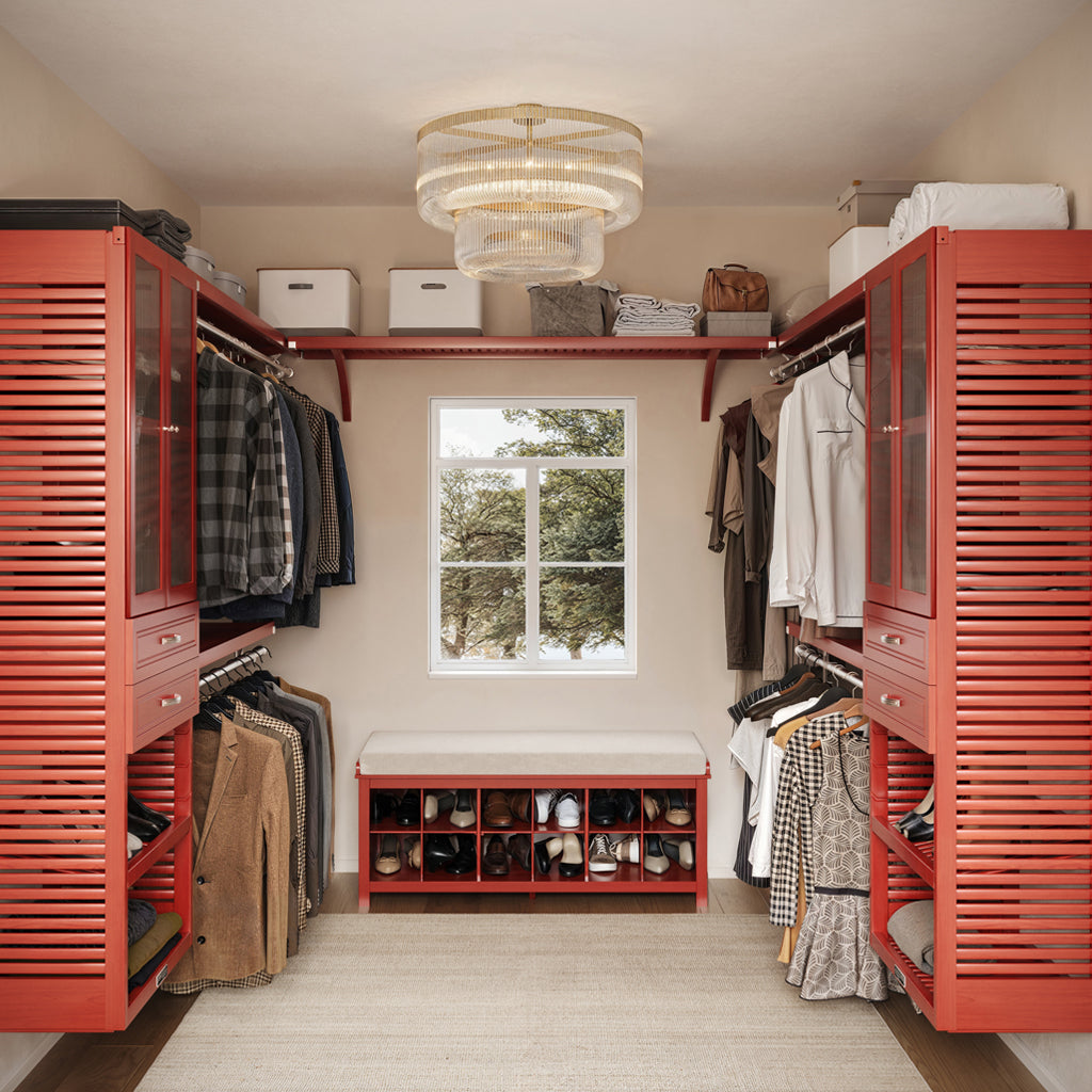 After walk-in closet with red wardrobes, clothes, and a bench.